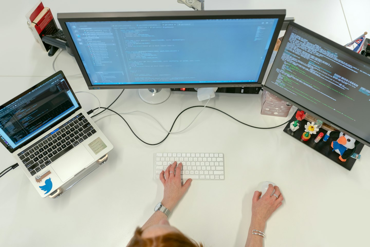 Programista kodujący na stanowisku z wieloma monitorami w biurze.